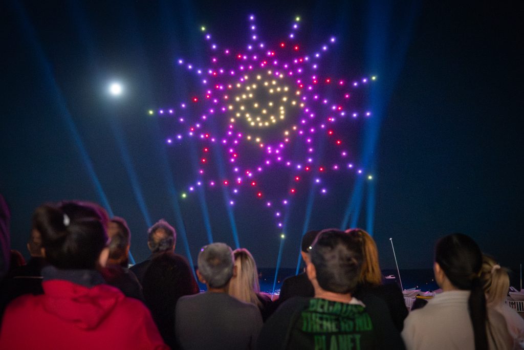 Drone show in the night sky of Lloret de Mar, forming vibrant light patterns on a dark background.