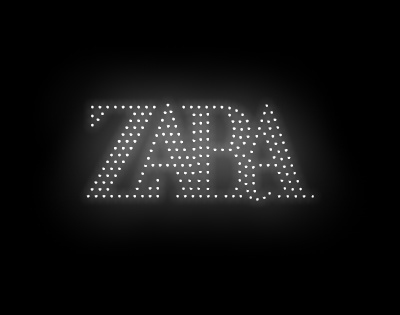 Drones formando o logotipo da Zara no céu noturno com luzes brilhantes.